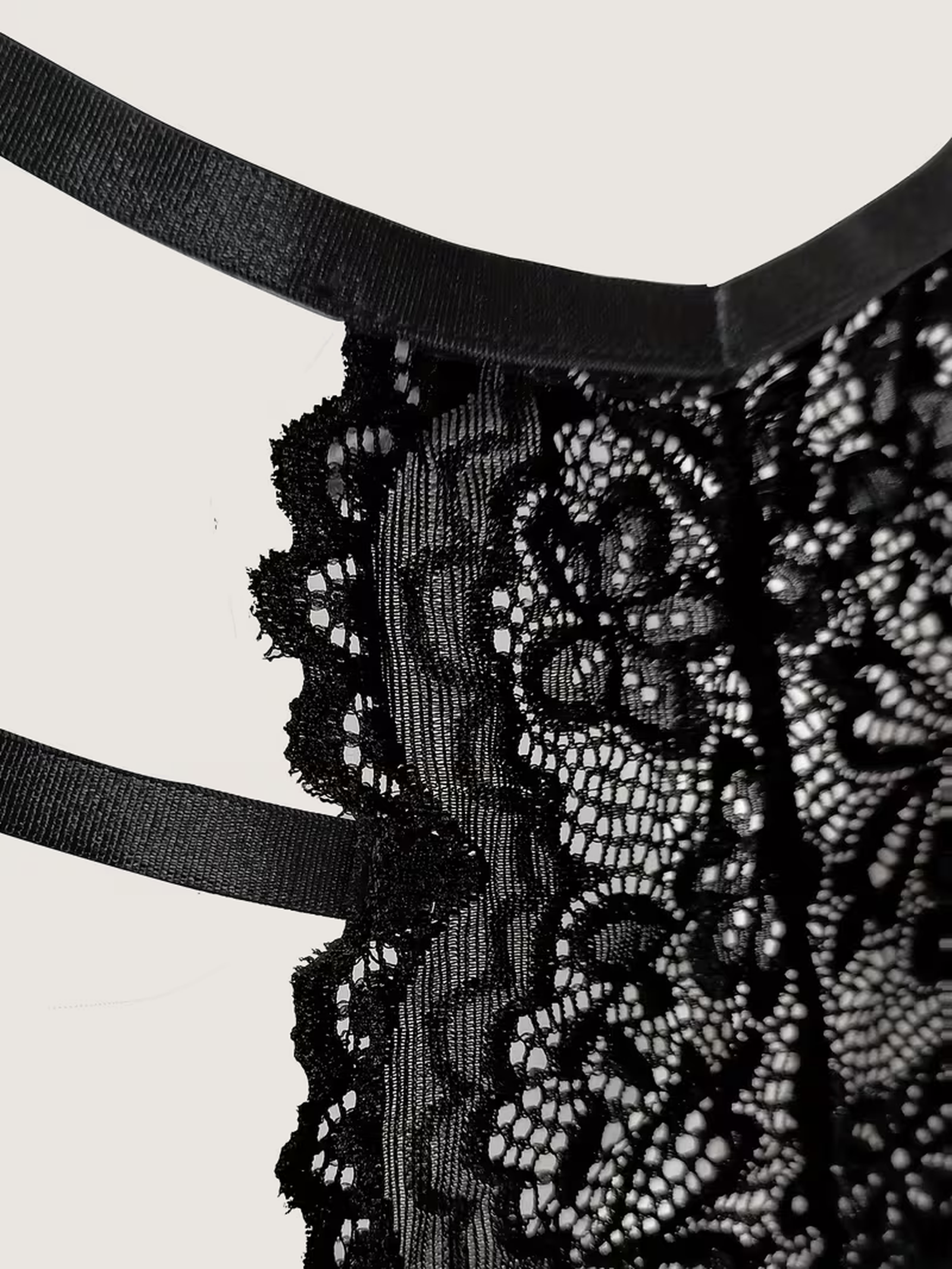 Macro detail of the scalloped floral lace and satin strap edging